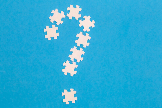 White puzzles in the shape of a question mark on a blue background, flat lay. - Powered by Adobe