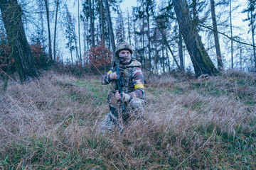 Ukrainian soldier on the front line. With an assault rifle in camouflage. Yellow tape.
