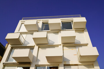 new modern white facade building with square balcony and cube terrace in blue sky