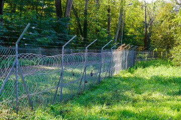 fence wall and barbed wire barrier as a secret private place or military base in nature green...