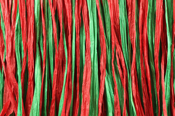 Background - red and green paper raffia strips situated in parallel lines