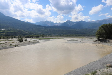 Beautiful panoramic view over a flowing river in the French Alps, region Hautes-Alpes.