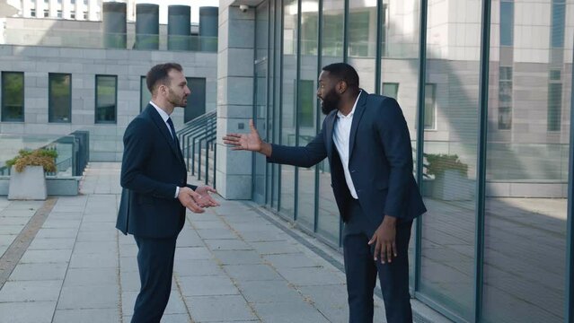 Angry man boss scolding an employee for a bad job while standing near the office building. The tyrant boss yells at his subordinate and insults him, showing personal contempt. Conflict at work concept