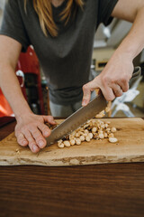 Female hands chopping hazelnuts for cooking pastry.