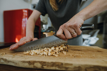 Fototapeta na wymiar Female hands chopping hazelnuts for cooking pastry.