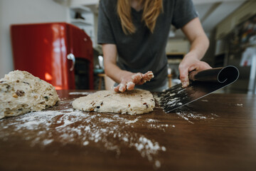 Fototapeta premium Female hands preparing dough for stollen with scraper.