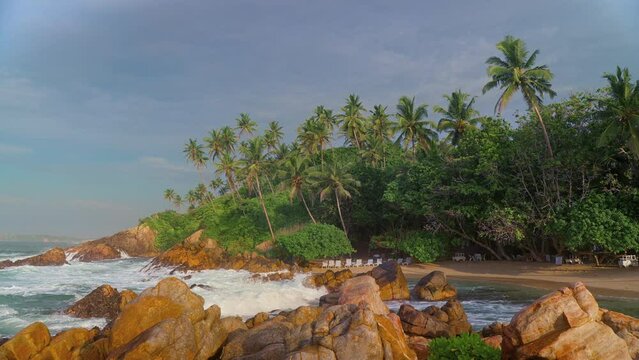 An exotic tropical deserted beach. Sunbeds on the beach under the shade of coconut palms. Marissa secret Beach in the south of Sri Lanka