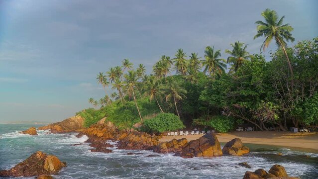 An exotic tropical deserted beach. Sunbeds on the beach under the shade of coconut palms. Marissa secret Beach in the south of Sri Lanka