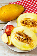 Table of fruits. Melon, papaya, and slices of apple on a wooden table. Selective focus, top view.