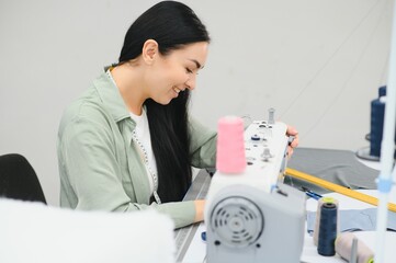 Obraz premium Beautiful young woman sewing clothes with sewing machine.