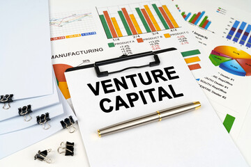On the table among financial graphs and charts lies a tablet with the inscription - Venture capital