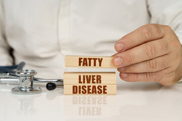 On a white surface, a stethoscope and wooden plates with the inscription - Fatty liver disease