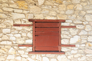 Vintage construction boarded wood red window, in brown stone construction.