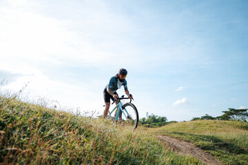 Obraz premium A young bearded cyclist is biking through a field