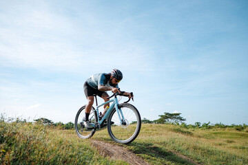 Fototapeta na wymiar A young bearded cyclist is biking through a field