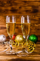 Two wineglasses with champagne and different christmas decorations on wooden table