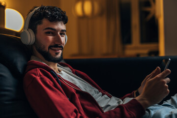 Man sits at home with headphones and looks at the camera