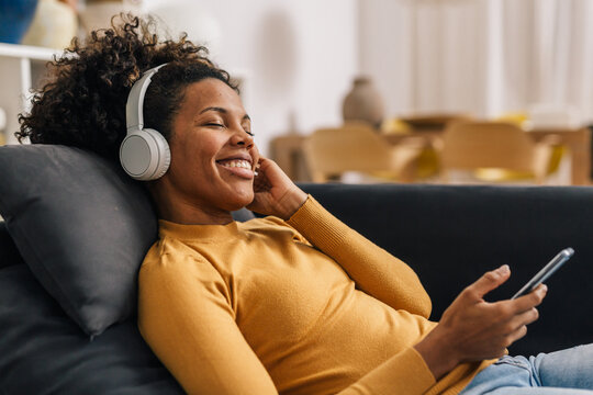 African American woman enjoys listening to music at home