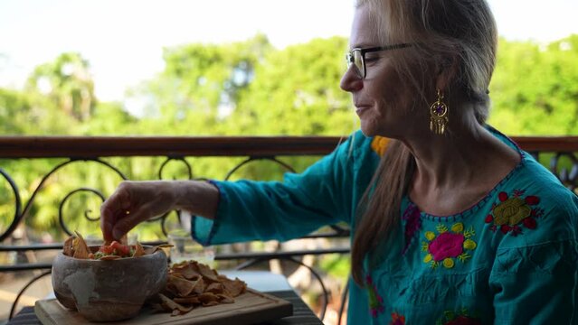 Beautiful Mature Woman Having Food At Outdoor Cafe On A Balcony With Amazing View Of Mexican Town. Woman Eating Guacamole At Resort Restaurant. 