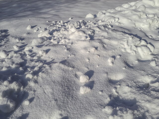 View of ground covered with piles of white snow in sunlight in winter