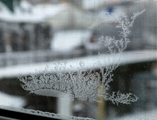 Frosty pattern pattern on window glass, beautiful pattern made frost on glass in cold winter weather