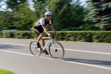 Photography in motion. A male cyclist rides a road bike, trains in a bicycle suit. Sports check-in in the city for a while.