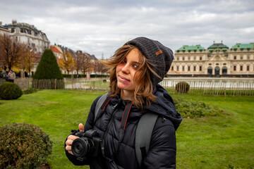 Young girl with camera posing in front of Schloss Belvedere in Vienna. Beautiful girl traveling in winter in Vienna. - 556546950