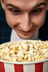 Young caucasian man in 3d glasses eating popcorn