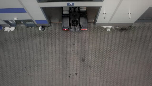 The truck tractor for international cargo transportation slowly drives out of the open garage gate in reverse. Transport and logistics, TIR.