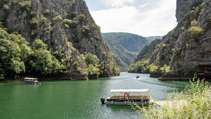 Matka canyon in North Macedonia near Skopje, boat on the lake, boat trip, Matka lake and mountain view with sky, colorful boat for tourists - obrazy, fototapety, plakaty