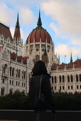 Obraz premium A female tourist stands in front of the Hungarian Parliament Building in Budapest vertical photo
