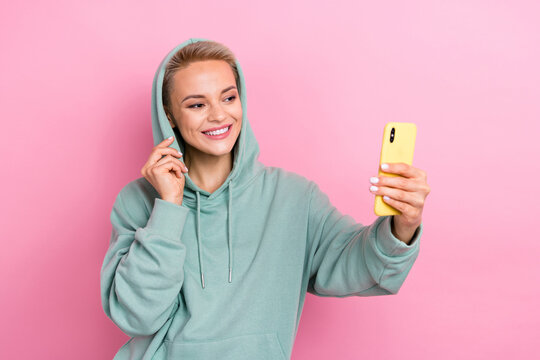 Photo of young cheerful girl positive satisfied good stats online viewers internet video stream hold her iphone isolated on pink color background