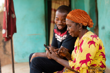 young african man assists an elderly woman using her phone