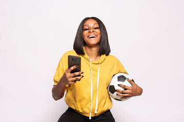 happy black lady holding a football and using her phone