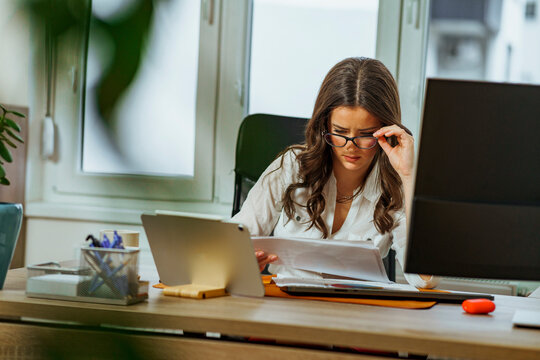 Young intern is having difficulties with her new assignment, she looks tired and confused as she looks at the chart