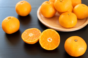 半分にカットしたみかんとたくさんのみかん