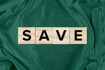 Saving Concept - Wood Tiles Spelling Out SAVE atop a Green Silk Background