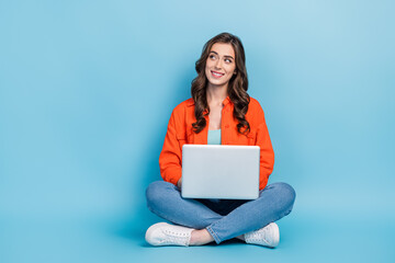 Full body photo of young lovely lady look empty space online education netbook wear trendy orange clothes isolated on blue color background