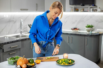 Young adult woman preparing vegetable salad in kitchen. Concept of healthy food, diet and eco food.