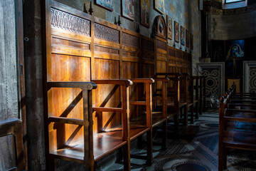 Detail of the wooden stalls, illuminated by a ray of sunlight, inside the church of Santa Maria...