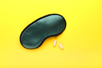 Earplugs and sleeping mask on yellow background