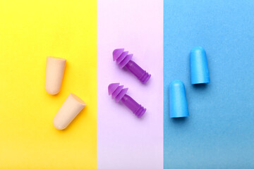 Different earplugs on color background