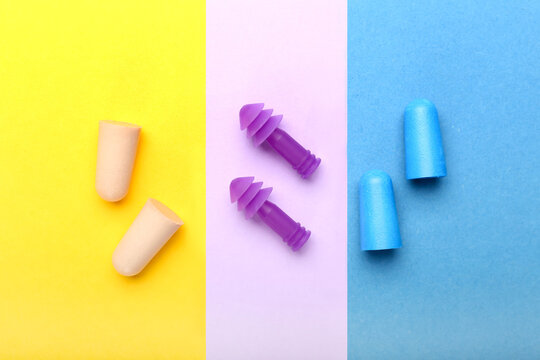 Different earplugs on color background