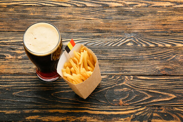 Glass of Belgium beer and french fries on wooden background