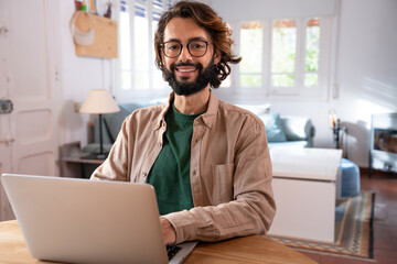 Cheerful young programmer looking at camera while working at his home. High quality photo