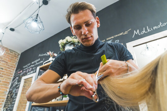 Portrait Of Male Hairdresser Using Scissors. Caucasian Mid Adult Man Using Professional Hairstyling Equipment. Low Angle View. . High Quality Photo