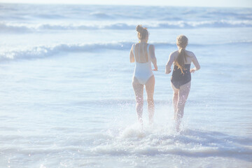 stylish mother and teenage daughter at beach running