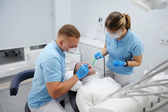 dentist patient assistant during her dental treatment at dentist. Dental doctors treating a male patient in hospital Doomsday Teeth Cleaning Doctor and assistant in blue Clean sterile clinic