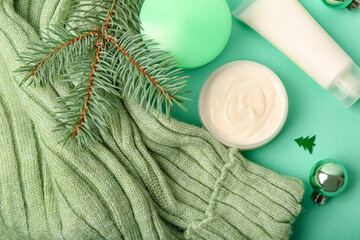Cosmetic products, sweater and fir branch on color background, closeup