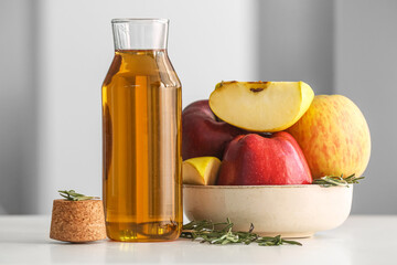Bowl with fresh apples and bottle of juice on table